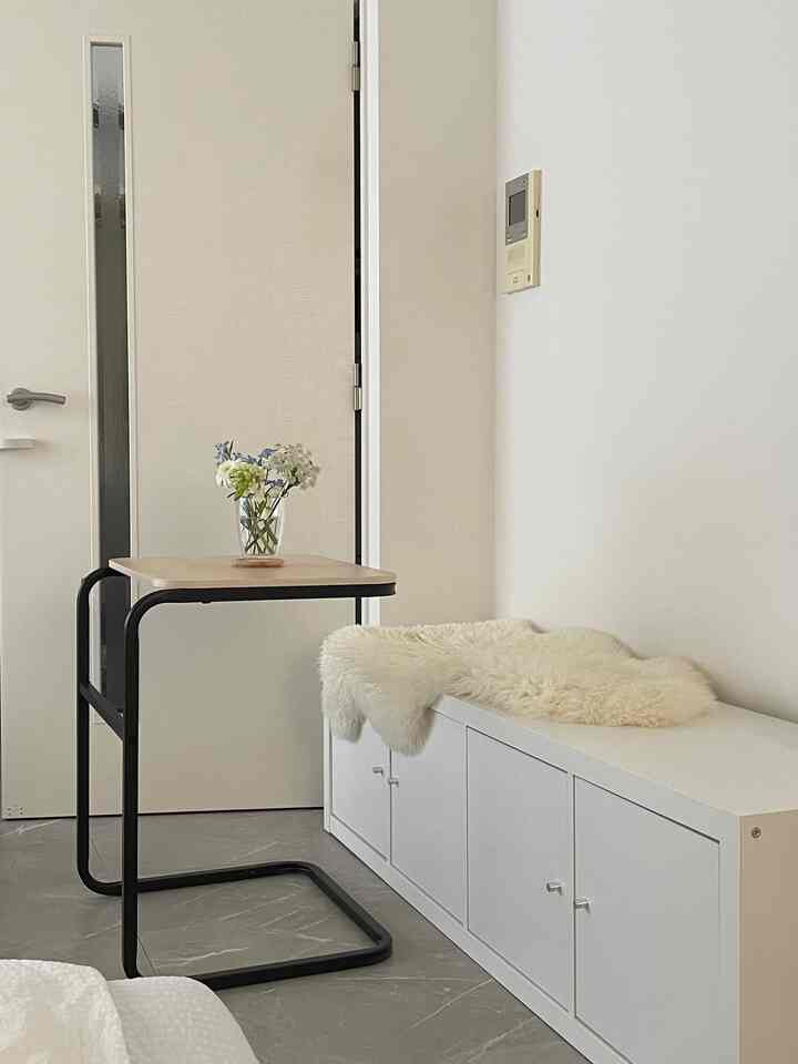 Natural color tone small living room featuring a white storage bench, black-framed side table, and natural sheepskin for a simple cozy space