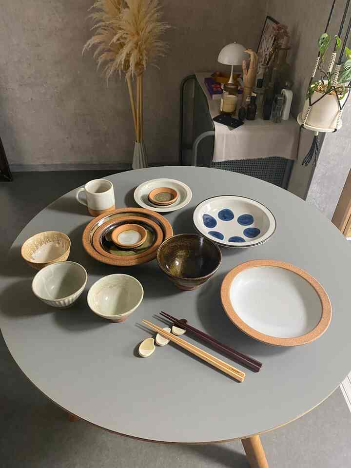 グレーのダイニングテーブルにさまざまな皿とボウルが整然と並べられたナチュラルな雰囲気のインテリア