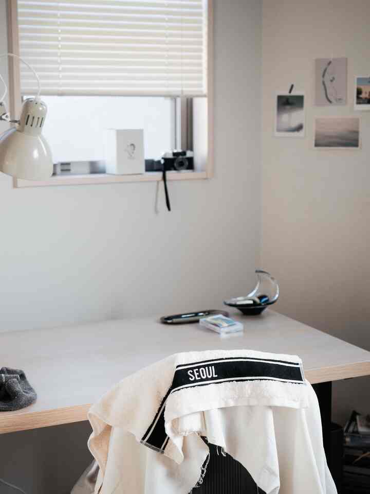 Bright and calm white and wood tone home office space featuring a simple desk and small table lamp for a clean atmosphere