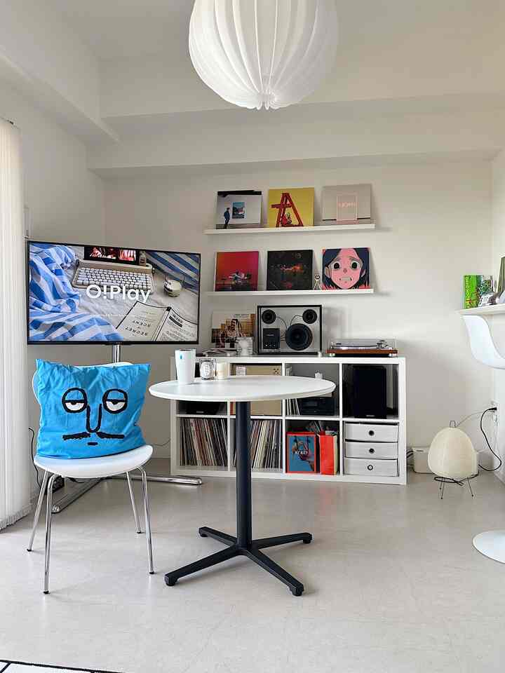 Bright white-toned small living room featuring a white round table with a blue cushion on the chair in center
