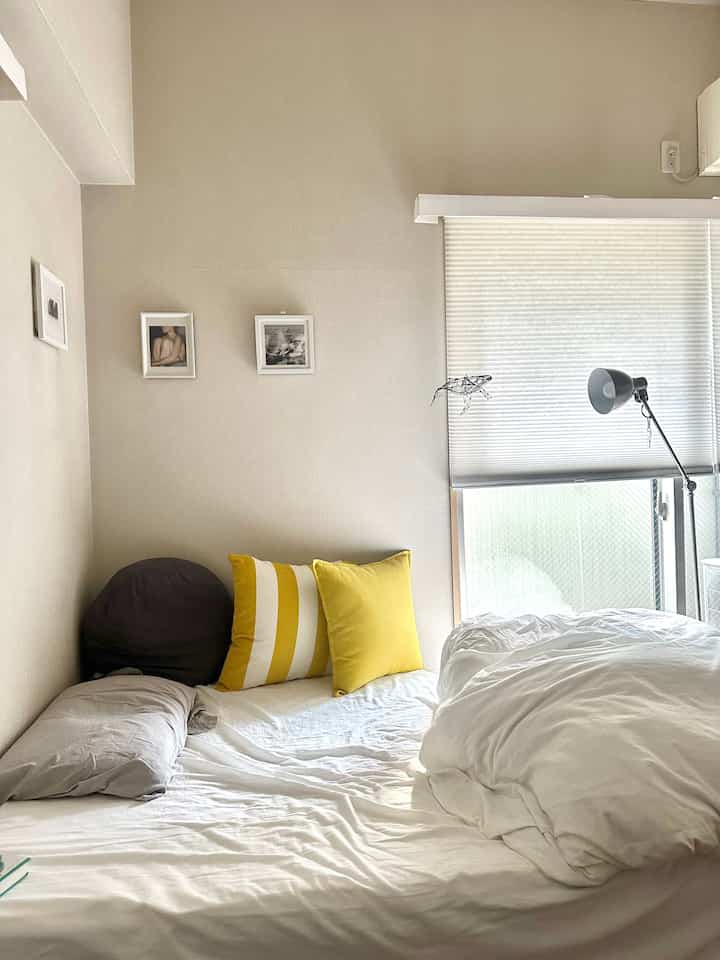 Natural-toned 6-tatami bedroom featuring white bedding and yellow cushions creating a cozy atmosphere
