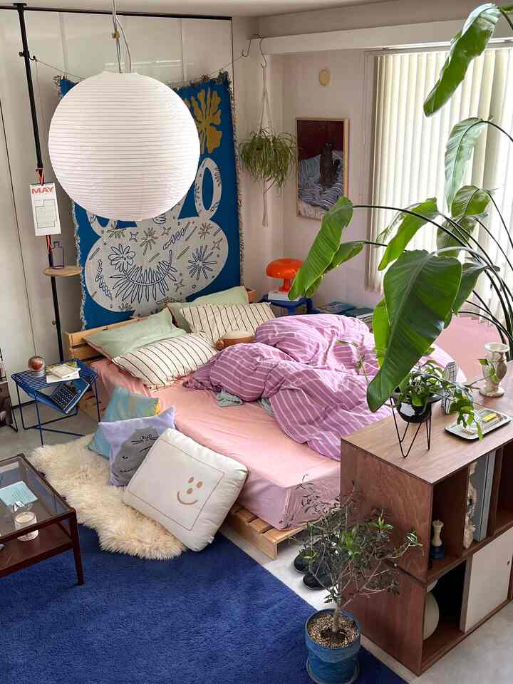 ブルーとナチュラルな色調の寝室、木製のベッドと多様なクッションが温かみのある雰囲気を演出するインテリア