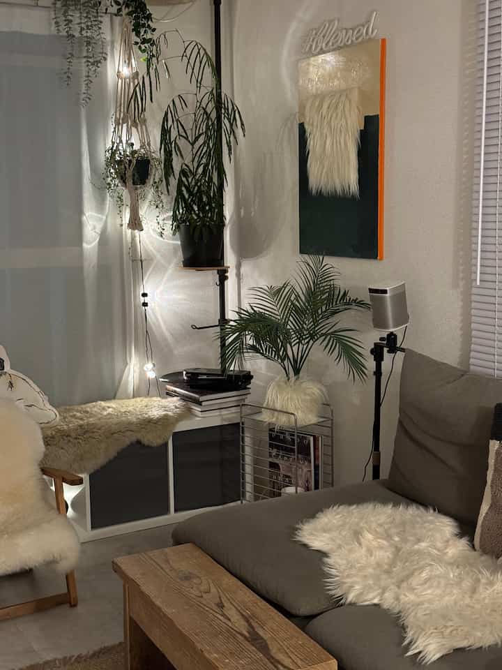 White and brown toned living room featuring natural plants, cozy sofa, and rustic coffee table with warm lighting ambiance