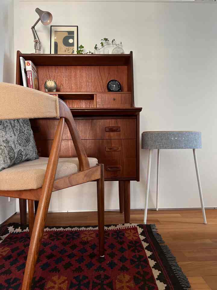 ライトブラウンの木材と白い壁が調和するスカンジナビアスタイルの小さな書斎空間、中型のデスクと椅子、ラグ、テーブルランプが配置された印象的なインテリア