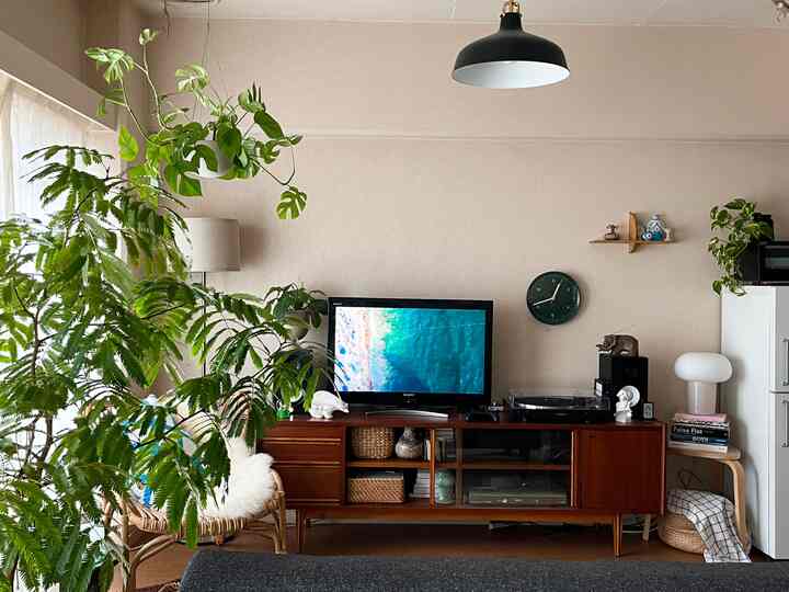 ナチュラルな色調のリビングルーム、ミッドセンチュリーモダンのテレビ台とテーブルランプが配置された雰囲気のあるインテリア