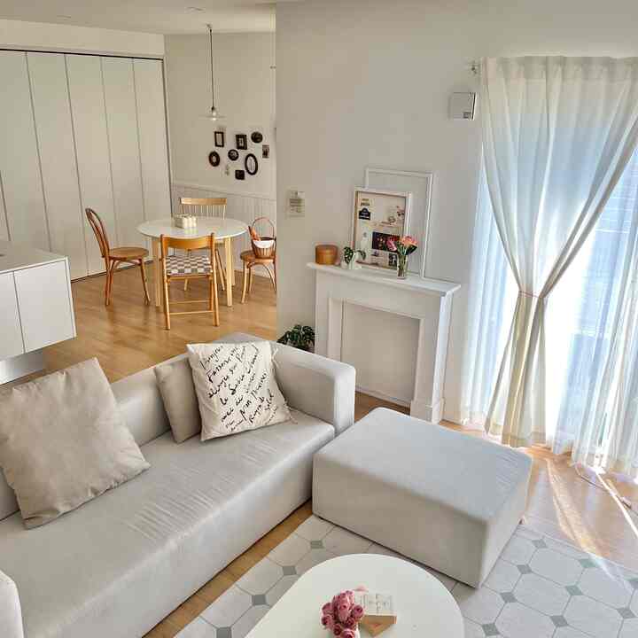 Bright white and wood-tone living and dining room featuring a simple sofa and ottoman in a cozy space