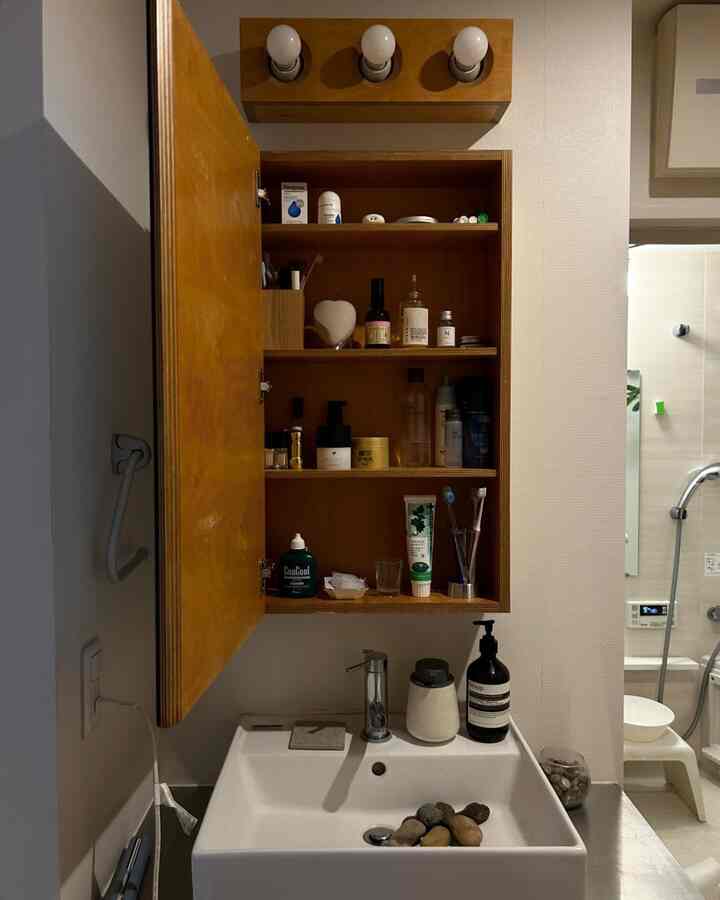 白と木目調が調和した清潔感のあるバスルーム、洗面台と収納棚が配置された雰囲気のあるインテリア