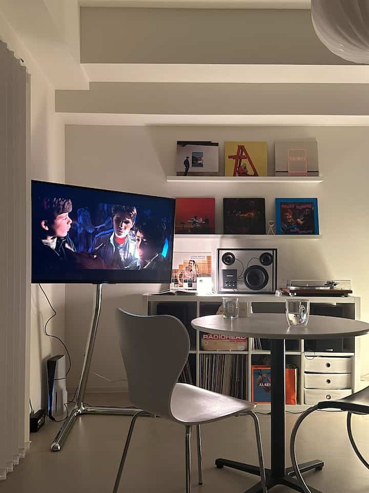 ホワイトカラーのモダンダイニング、壁掛けテレビとオーディオ機器が配置された雰囲気のあるホームシネマ空間