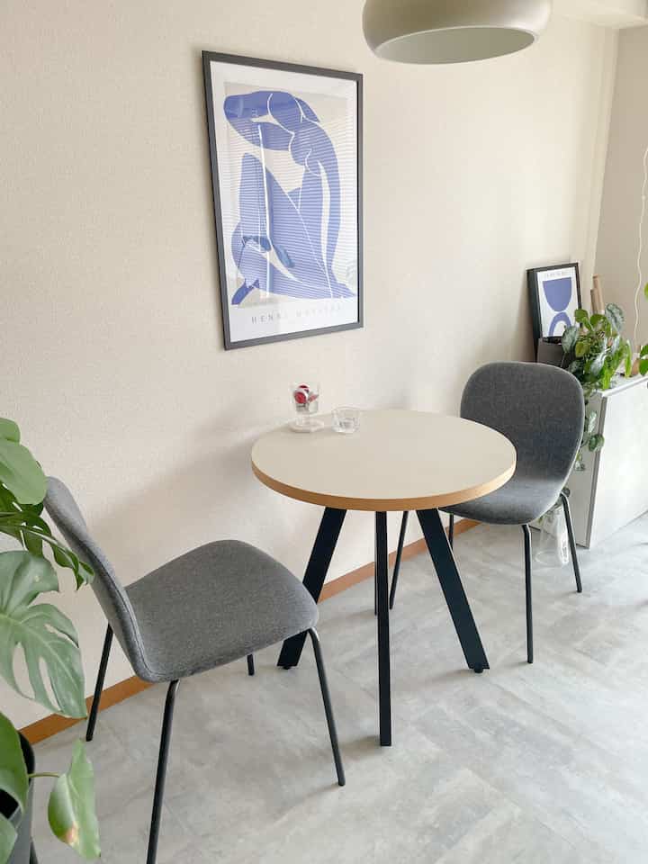 Natural color toned two-person dining room featuring a round dining table and gray chairs with a simple atmosphere