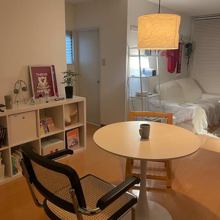 White and wood tone living and dining room featuring cafe-style round table and indirect lighting creating a cozy atmosphere