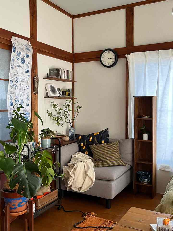 木目調とベージュが調和したリビング、グレーのソファと植物が配置された落ち着いた空間