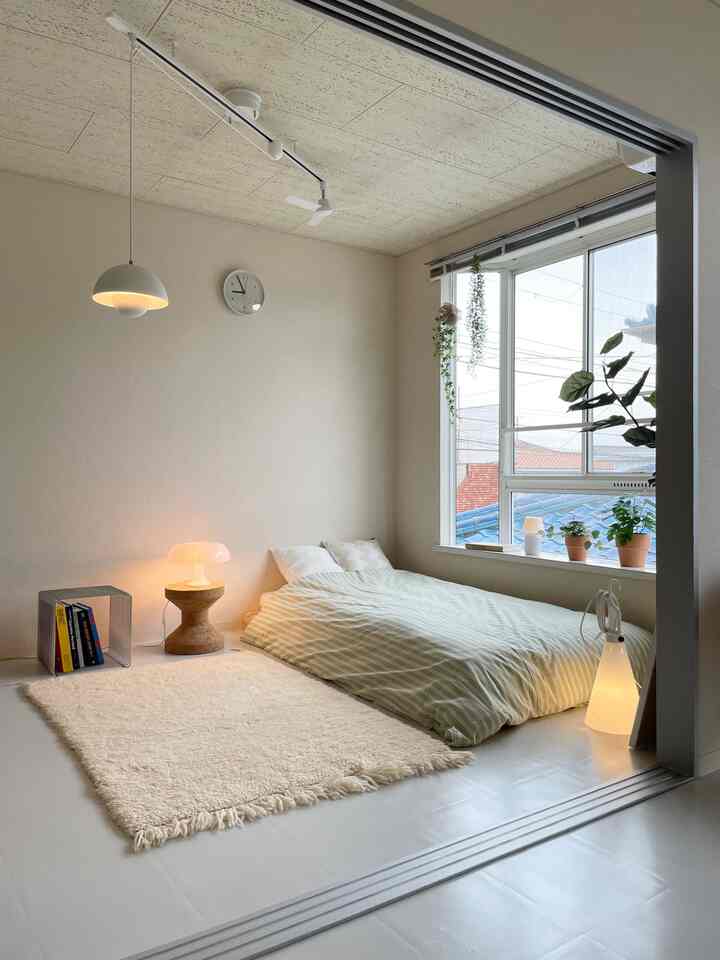 White and beige toned small bedroom featuring natural wood furniture and plants creating a cozy atmosphere