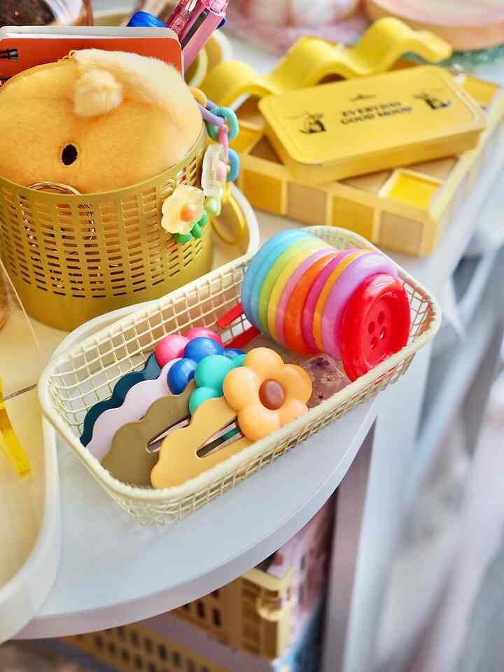 Yellow and pastel-toned decorative items arranged in a stylish storage setup