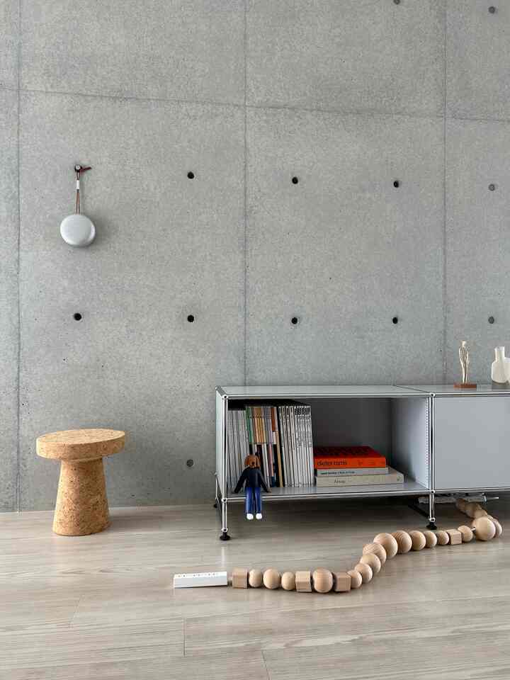 ライトグレー調のモダンなリビング、USMハラーの収納棚とコルクのサイドテーブルが配置されたシンプルなインテリア