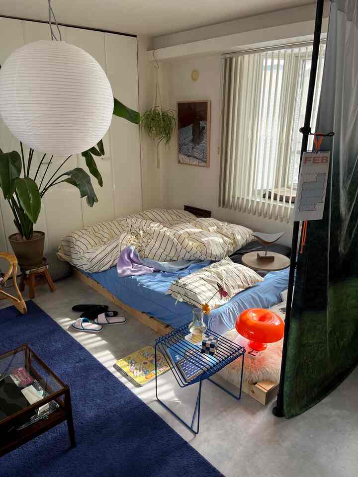 ホワイトとブルーのトーンが印象的な狭い寝室、木製ベッドと自然素材が調和した雰囲気のあるインテリア