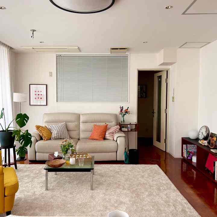 ホワイトとベージュのトーンのリビング、3人掛け電動リクライニングソファと植物が配置された落ち着いた空間