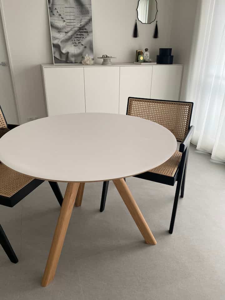 白と木目調が調和するダイニング、丸いダイニングテーブルとラタンの椅子が配置されたモダンな空間