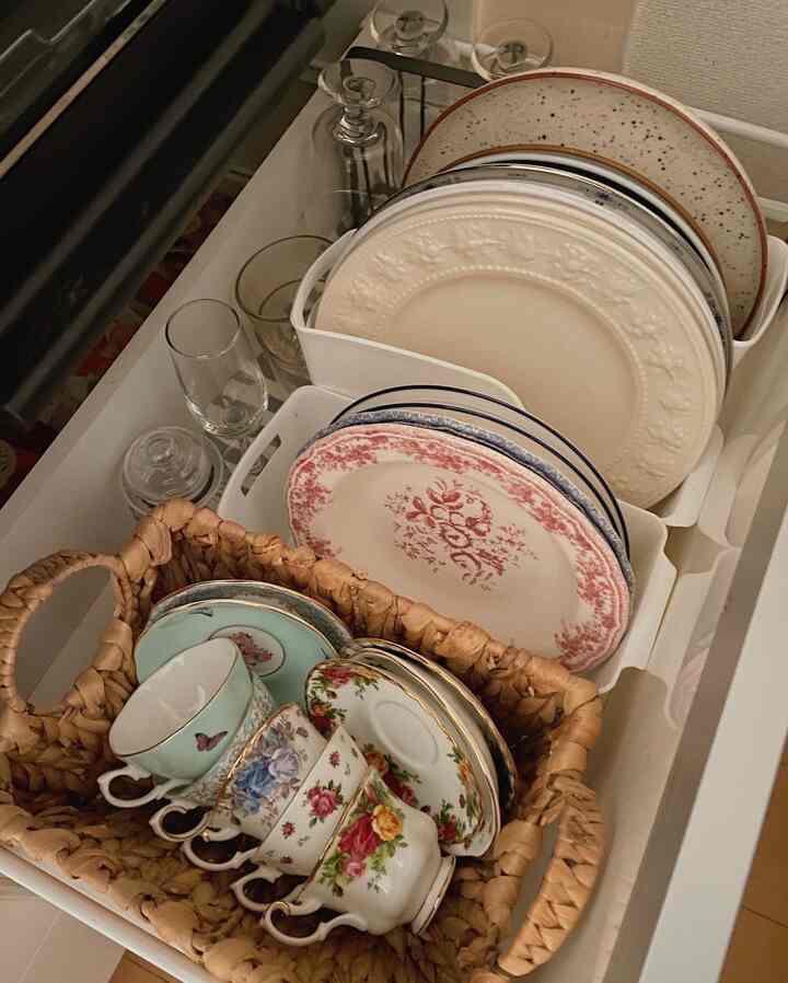 White kitchen drawer featuring plates and floral teacups neatly organized with practical storage ideas