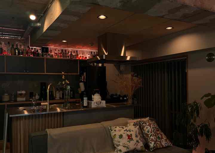 暗めの照明が印象的なインダストリアルスタイルのリビングとホームバー、ブラウンとブラックのトーンで構成された空間