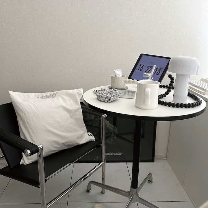 Minimalist home office space in black and white tones featuring a modern armchair and round side table with a sleek atmosphere