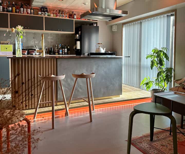 A minimalistic home bar space featuring wood tone and gray hues, with plants and clean design for a cozy atmosphere