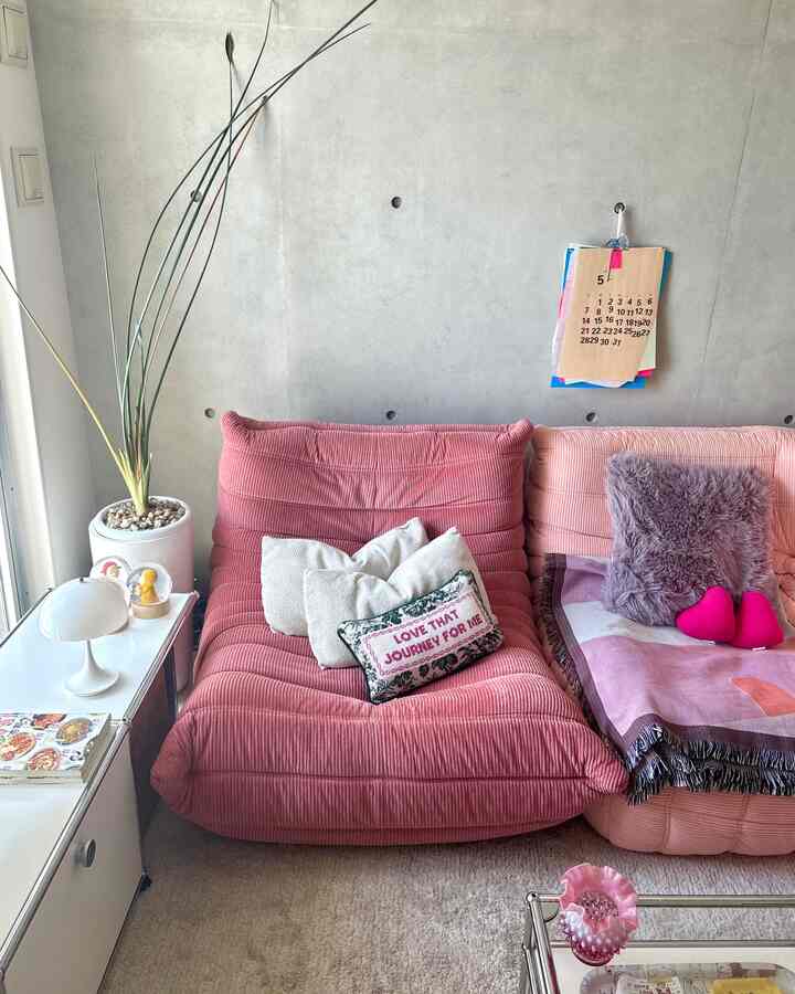 ピンクのソファとクッションが置かれたナチュラルモダンなリビング、植物とテーブルランプがある落ち着いた雰囲気のインテリア