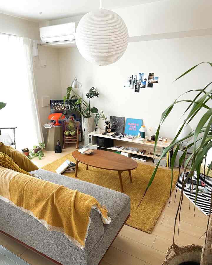 Yellow-toned living room featuring wooden coffee table, gray sofa, and plants with a cozy natural atmosphere