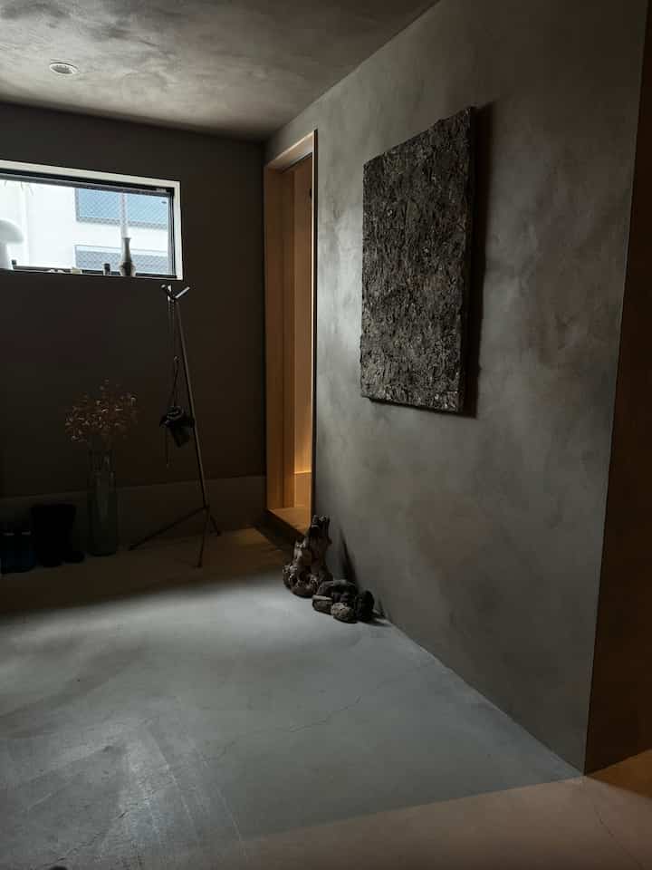 グレーとベージュのナチュラルカラーの玄関、ミニマルな家具とテクスチャーアートが配置された落ち着いた雰囲気のインテリア