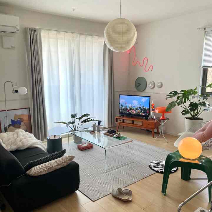 白と緑のトーンのリビング、ミッドセンチュリーモダン家具とガラステーブルが配置された雰囲気のあるインテリア