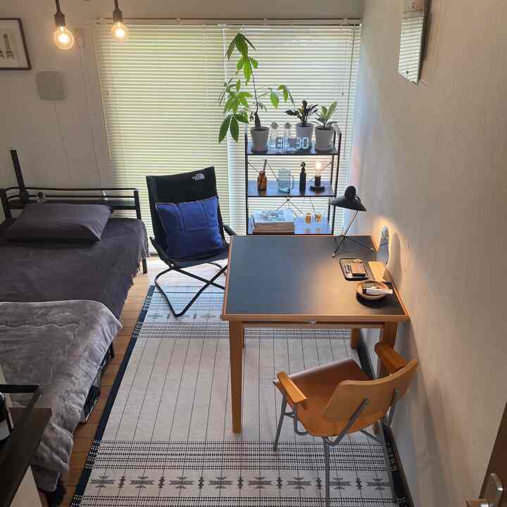 A warm living room with brown wood tones and black accents, featuring a mid-century modern desk and a camping-style armchair for a single household