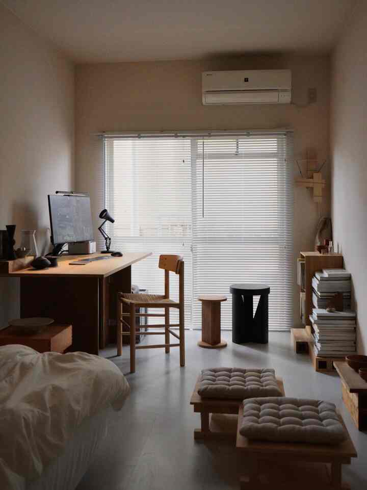 An ivory-toned small room featuring wood tone furniture and a minimalistic home office setup for a single household