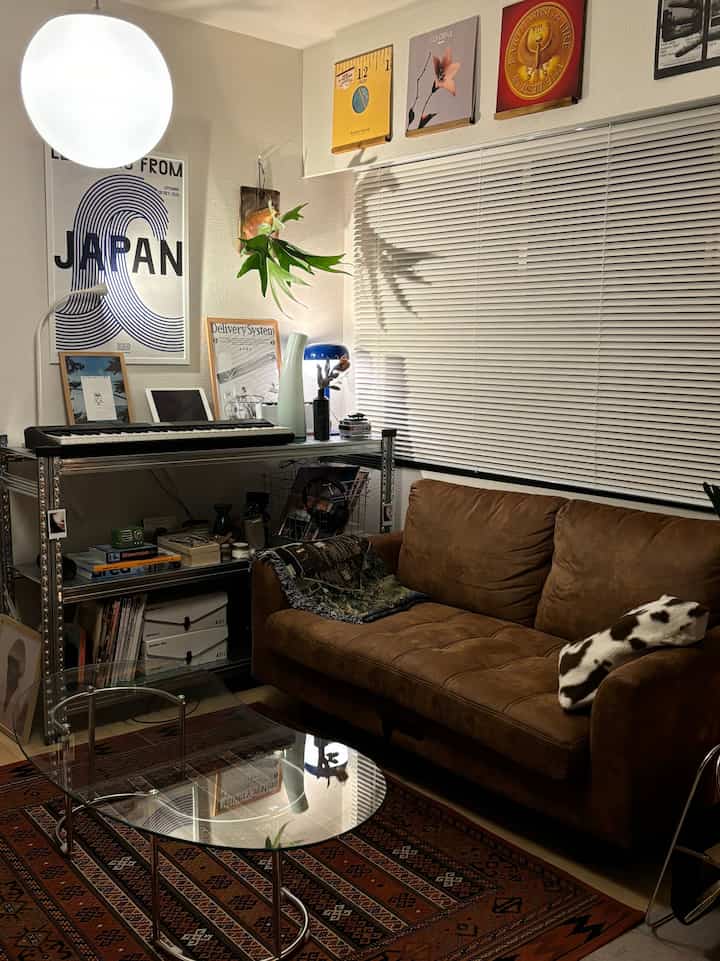 ホワイトの壁とブラウンのソファが配置されたナチュラルモダンなリビング、間接照明と植物の影が雰囲気のあるインテリア