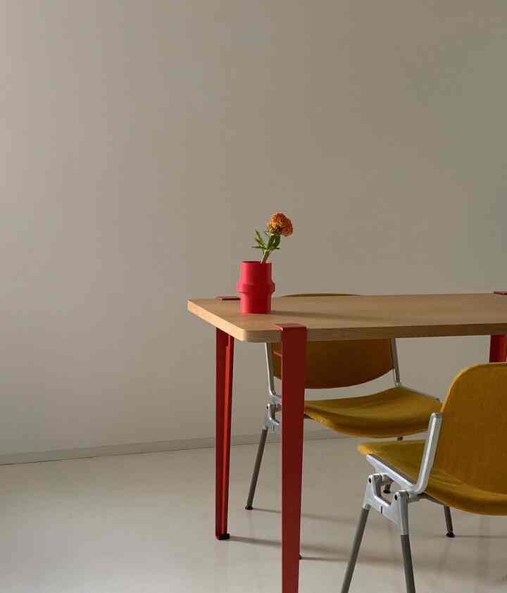 赤い脚のダイニングテーブルとマスタード色のスタッキングチェアが配置されたナチュラルな雰囲気のシンプルなダイニングルーム