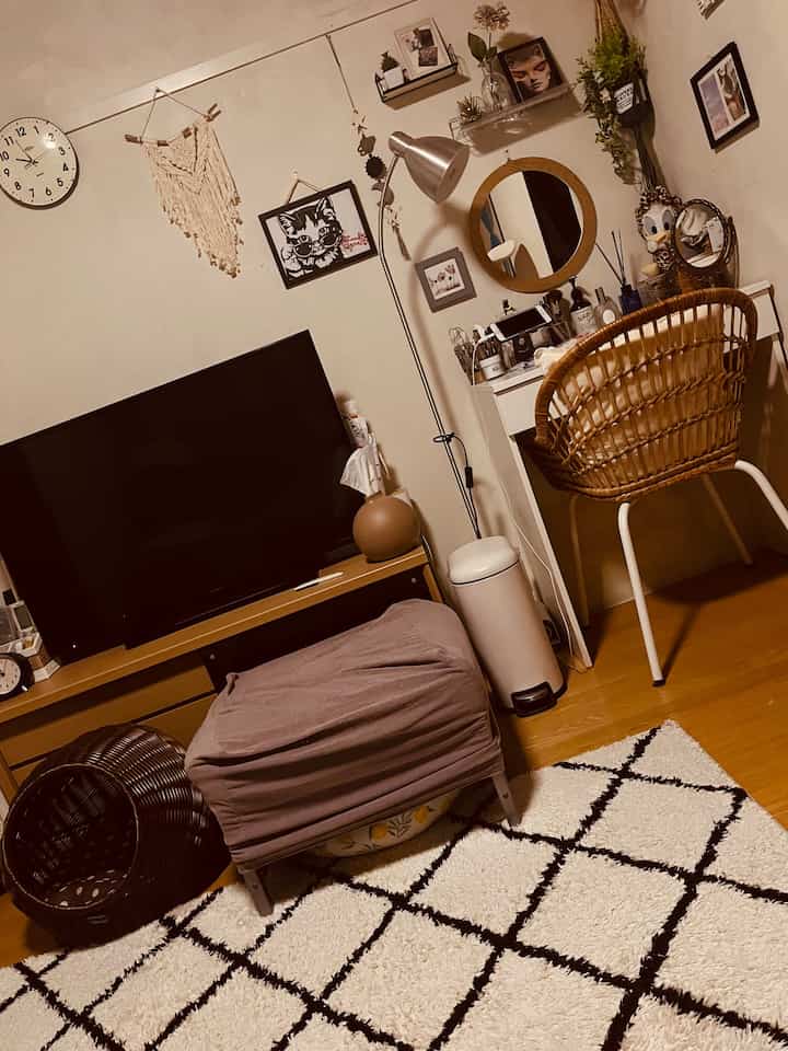 Compact single household vanity space with white walls, brown flooring, and rattan chair, styled for makeup use
