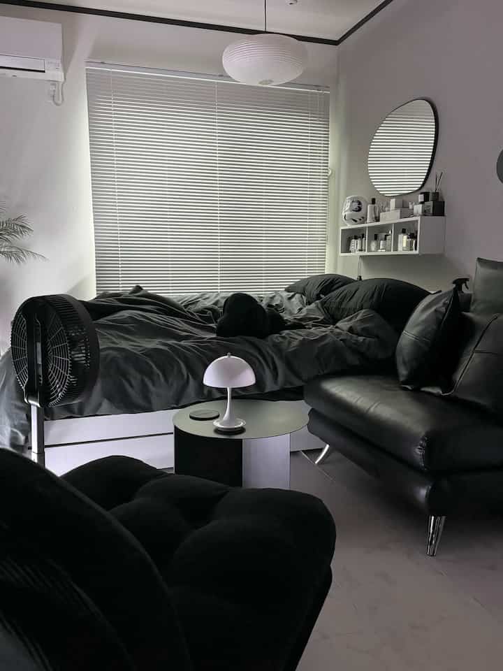 モノトーンの寝室、中央に黒いベッドと右側に黒いソファと椅子が配置されたシンプルな空間