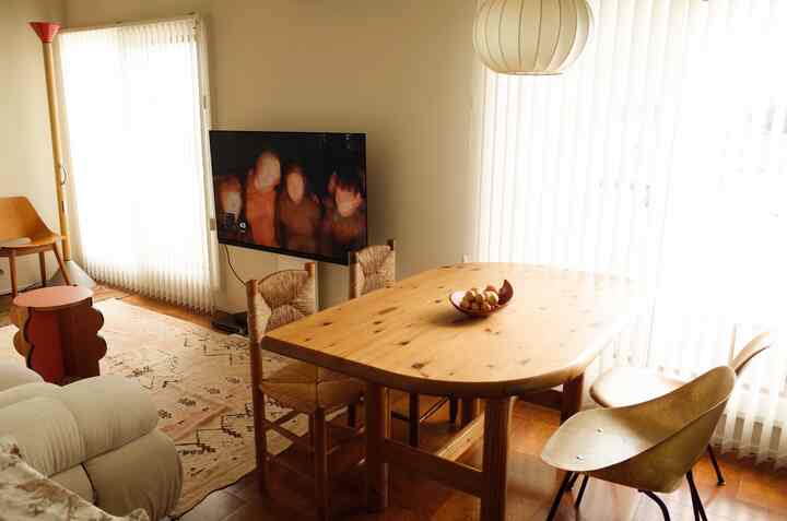 ナチュラルなブラウンの木目調とベージュの調和がとれたダイニング、ヴィンテージの食卓と椅子が配置された温かみのある空間