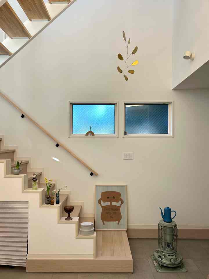 ナチュラルな木目調と白色の調和が美しい玄関、階段下の収納とモビールが配置された印象的な空間