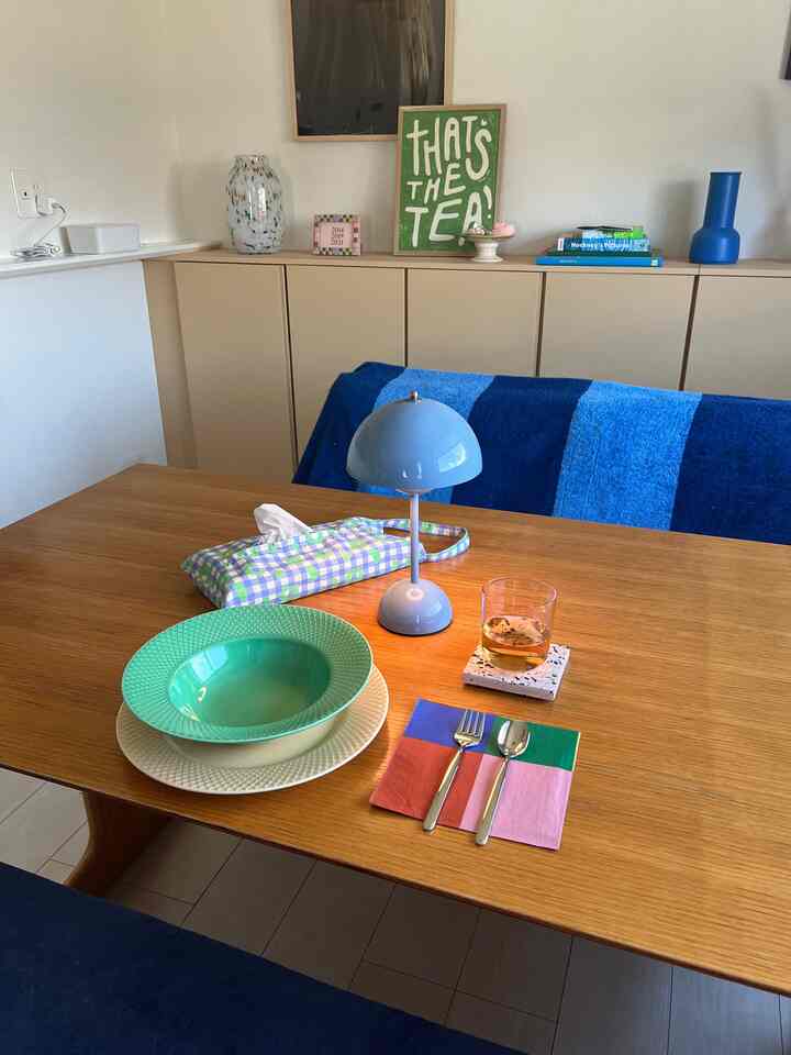 ナチュラルカラーとブルーのアクセントがあるダイニングルーム、木製のダイニングテーブルや食器、照明、壁のデコレーションが調和した印象的な空間