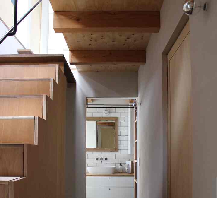 ナチュラルな木目調の階段とタイル壁が調和した印象的なパウダールームの空間