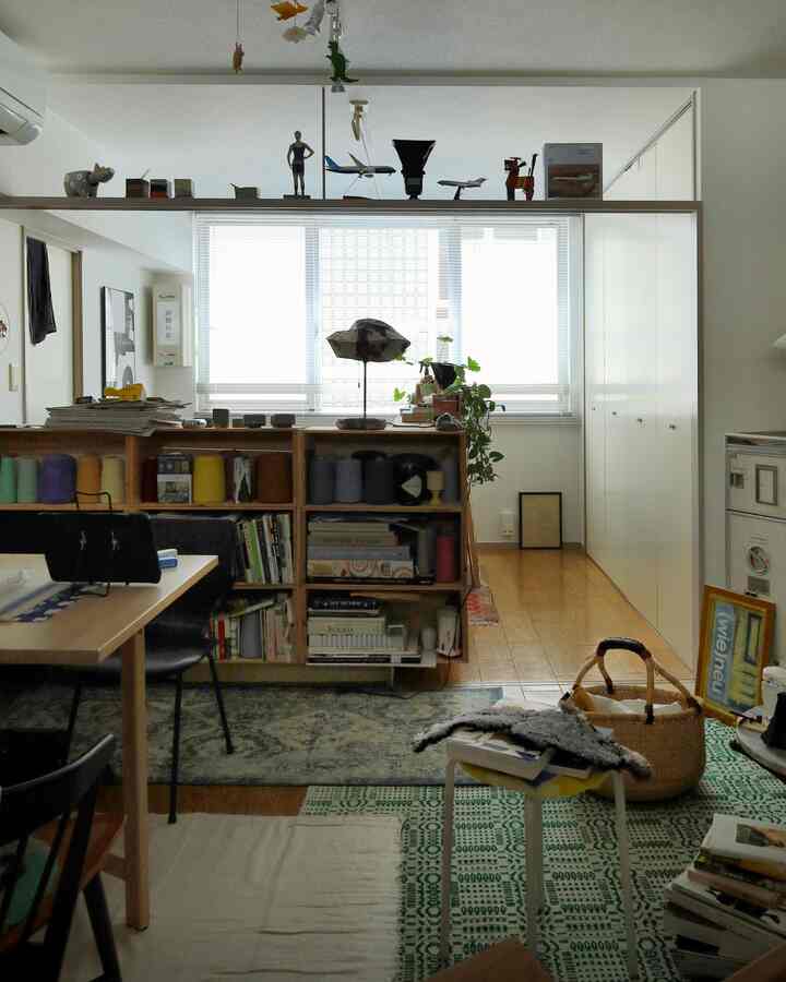 A white and wood-toned single household featuring a compact bookshelf with storage ideas and a handmade floor lamp in a cozy room