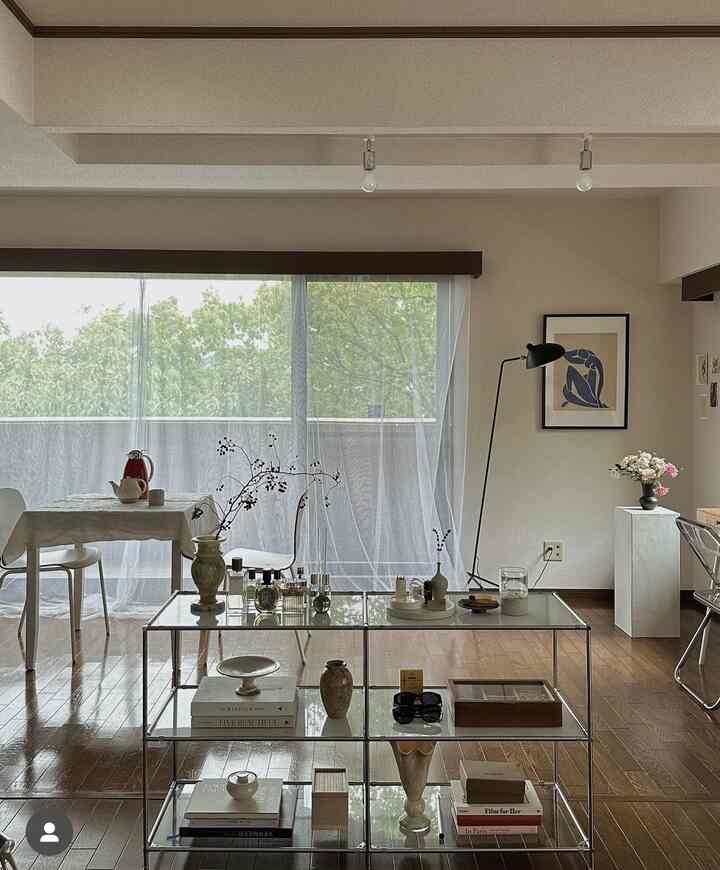 White and wood-toned living room featuring glass coffee table and simple furniture with a clean natural modern interior