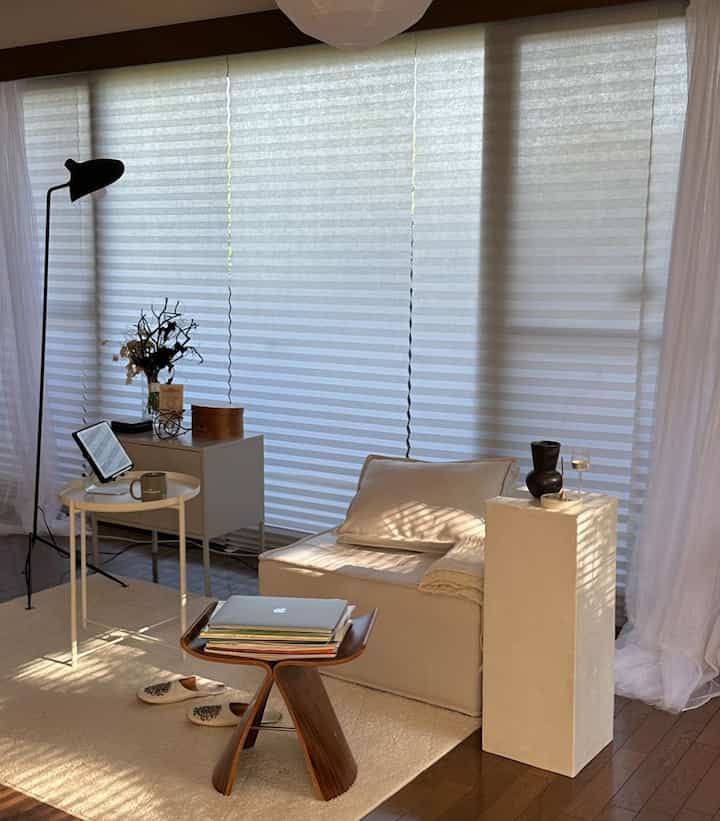 白と茶色の色調のリビング、ナチュラルモダンスタイルの一人暮らし空間で、コンパクトな配置と在宅勤務環境が調和したインテリア