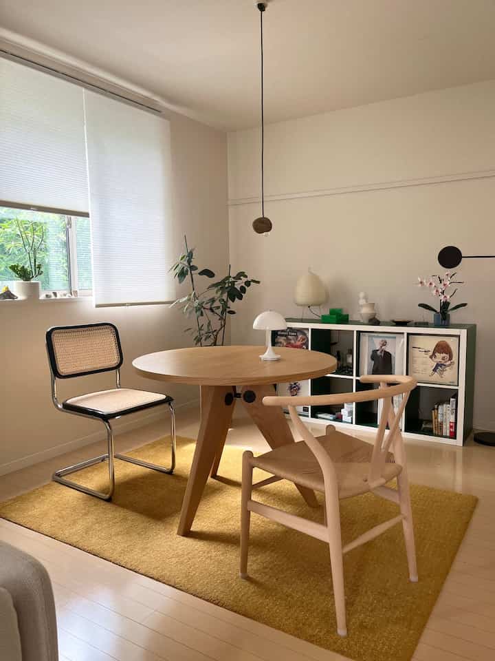Yellow rug under round wooden dining table with two chairs in a natural tone dining room interior