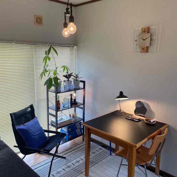 Mid-century modern single household room featuring orange-toned wood dining table with black top and blue cushion accents