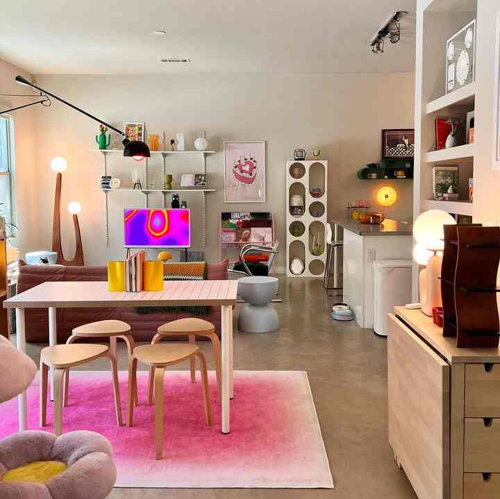 A cozy living and dining space with soft natural and white tones, featuring stools, lighting, and wall art decorations