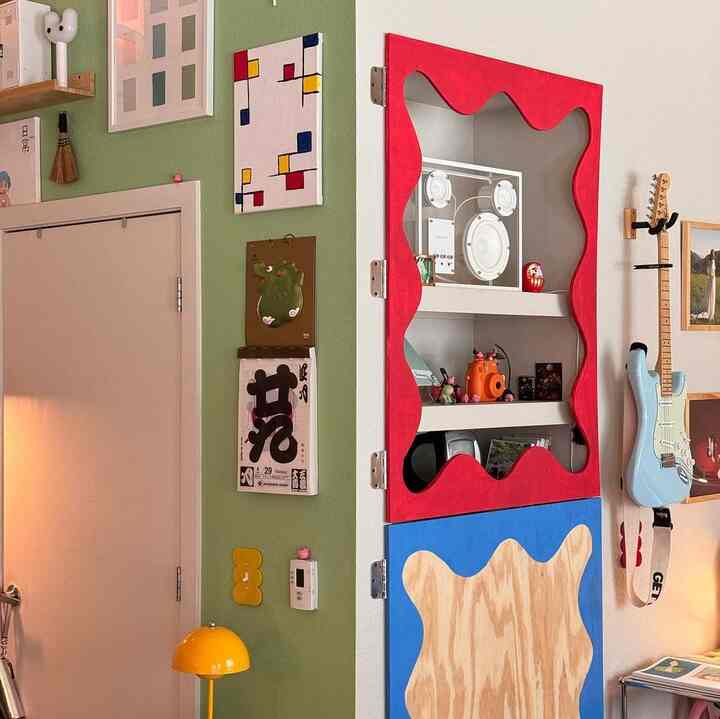 Modern, eclectic interior space featuring a dominant green accent wall, a unique red and blue cabinet, and a light blue guitar on the wall