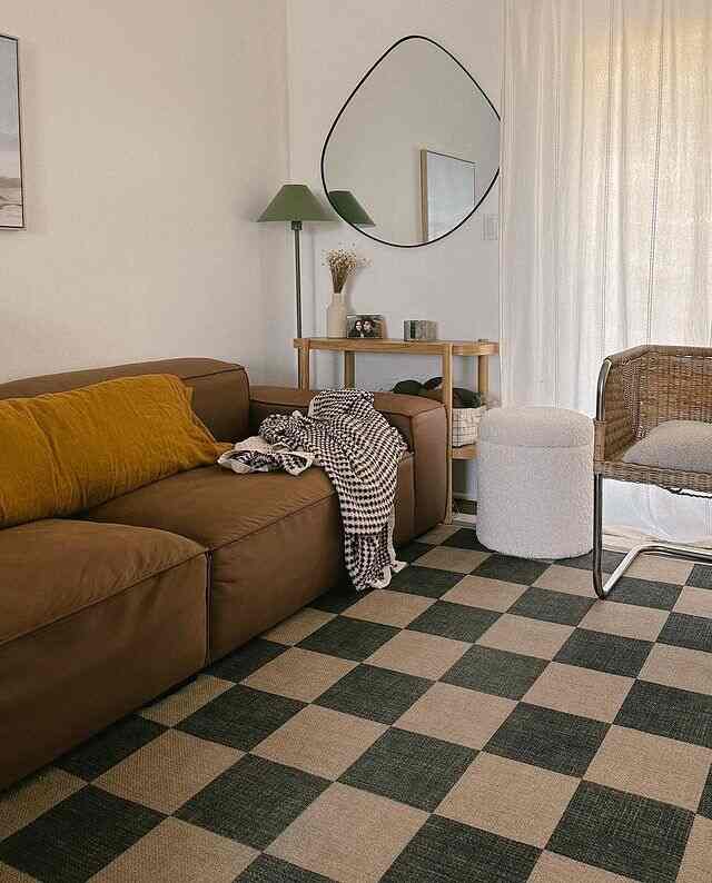 A natural brown-toned living room featuring a checkerboard rug, green floor lamp, and console table with cozy ambiance