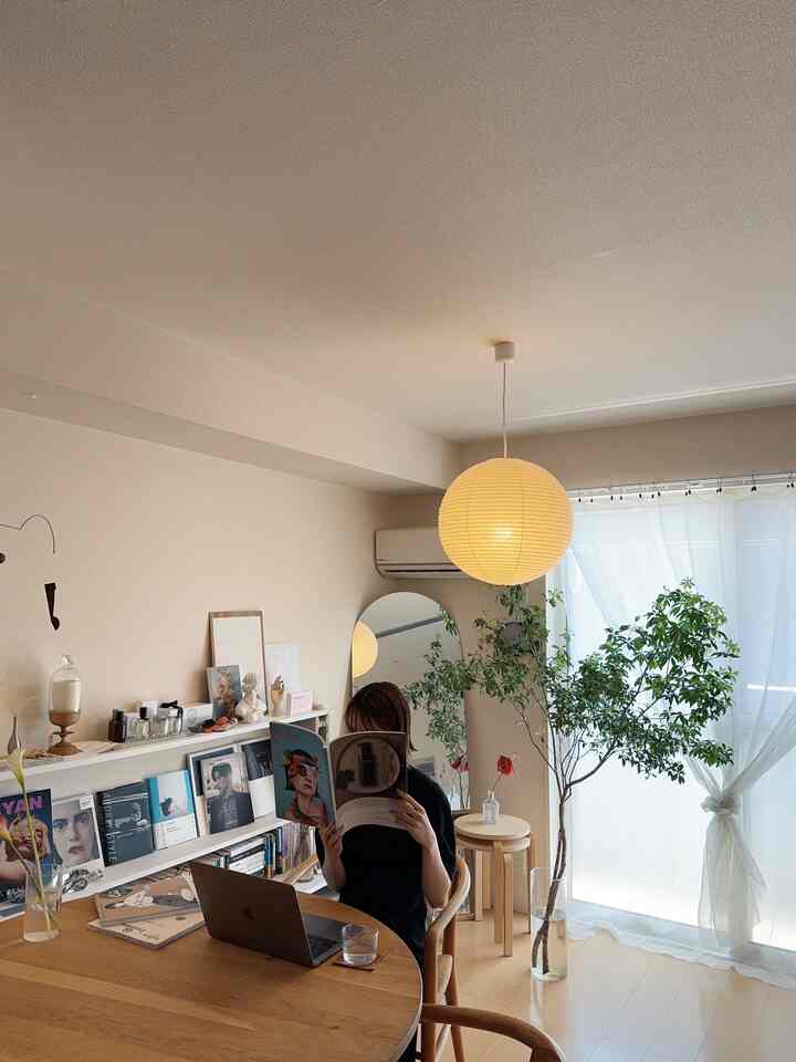 明るいホワイトと温かみのあるウッドトーンの1LDKリビング、ダイニングテーブルとペンダントライト、植物が配置された自然なモダンなインテリア