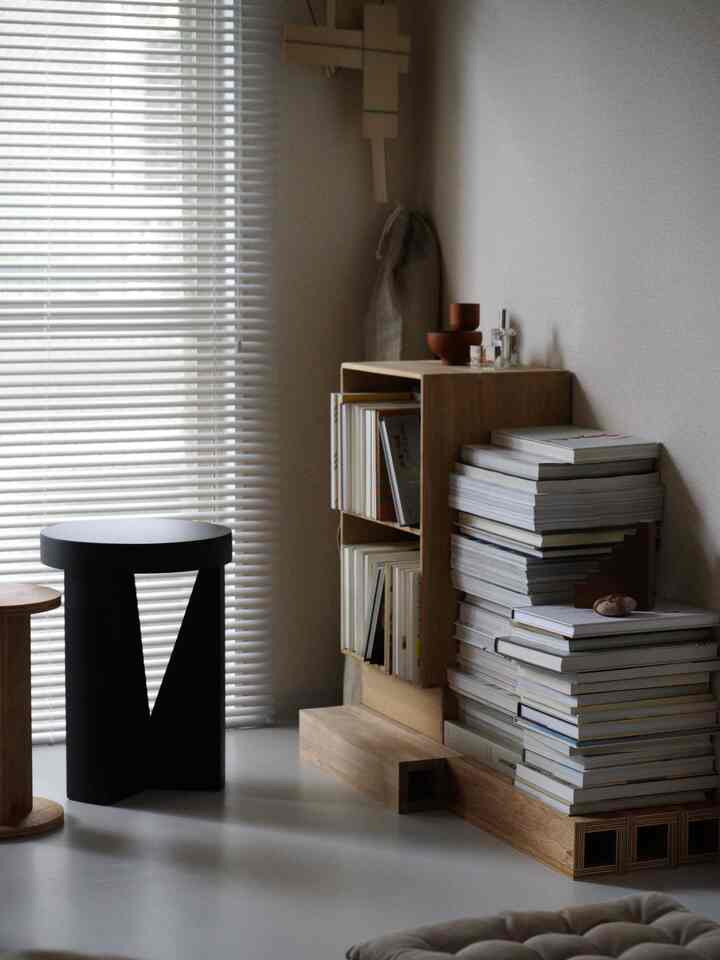 Gray-walled Nordic style study featuring wood tone bookshelf, blinds and stools in a simple, minimalistic interior