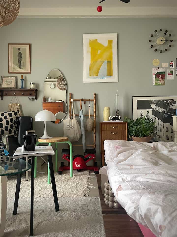 Bright white and green toned bedroom featuring mid-century modern furniture, rug, and stools creating a cozy atmosphere